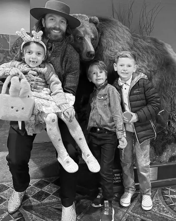 Family posing with bear statue indoors.