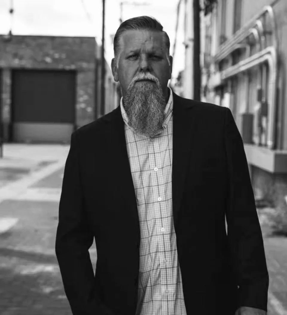 Man with beard in urban street setting.