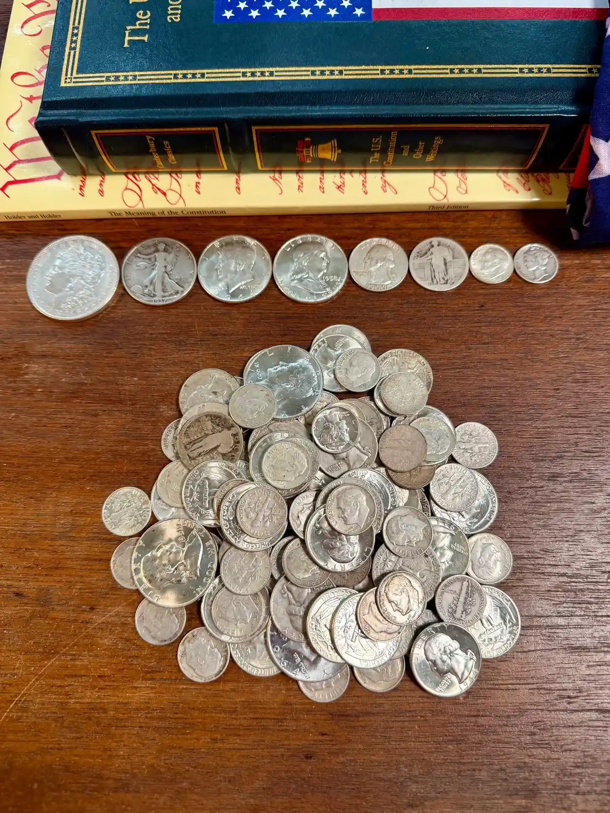 Coins on wooden surface beside books.