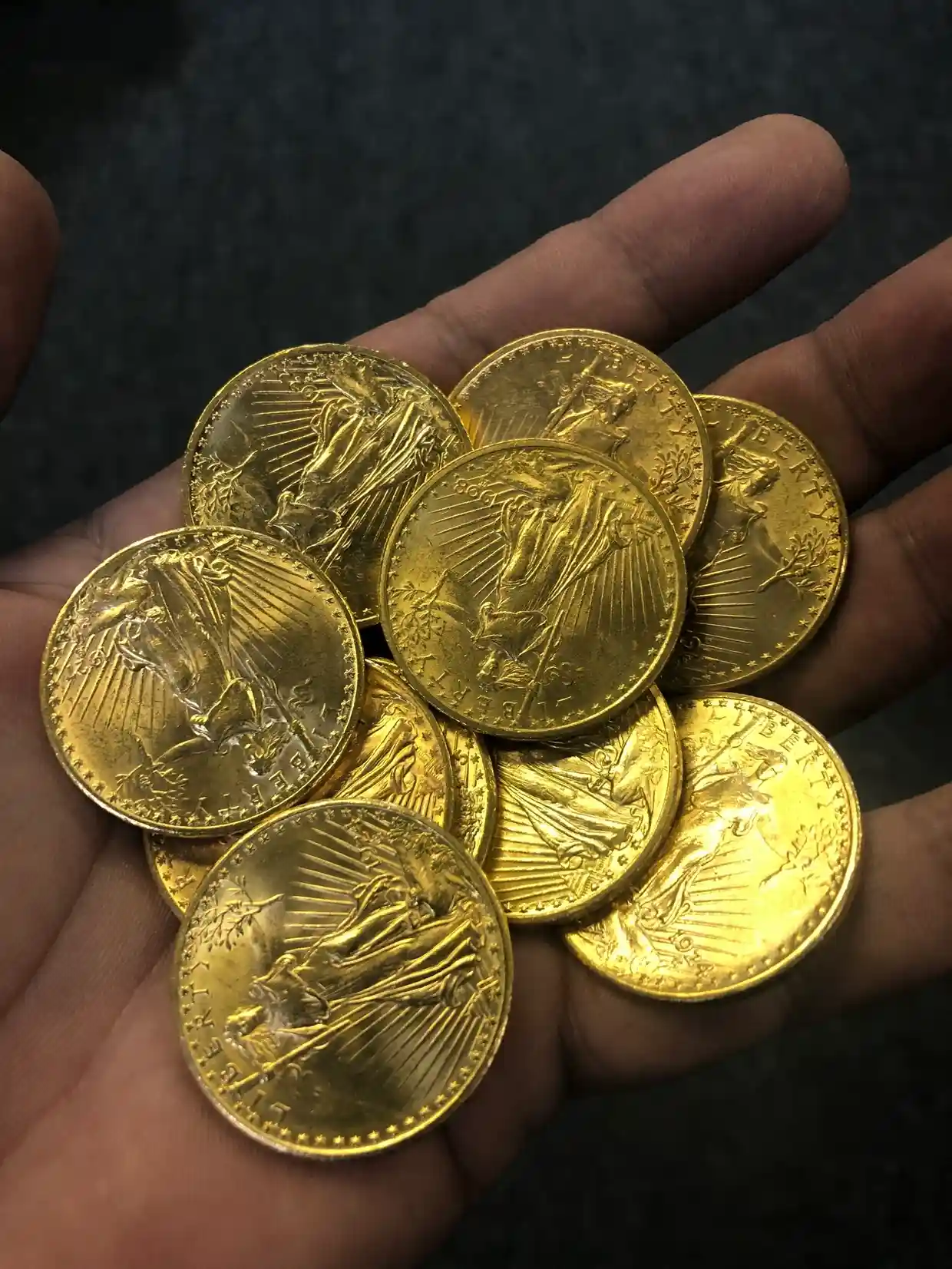 Hand holding several shiny gold coins.