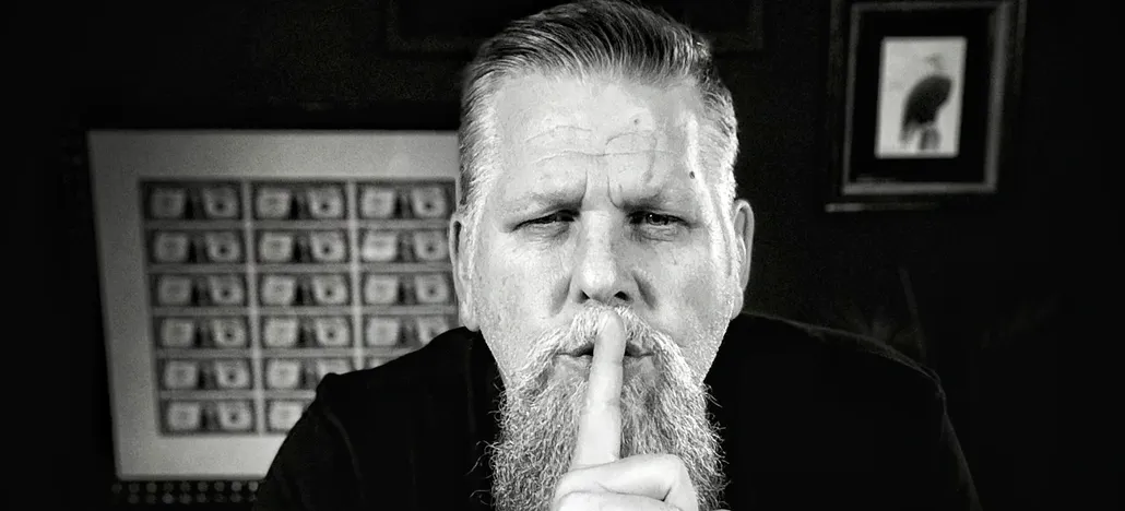Man with finger on lips, shushing gesture.