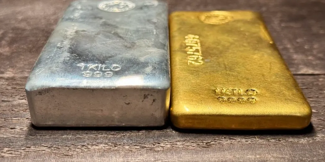Silver and gold bars on wooden surface.