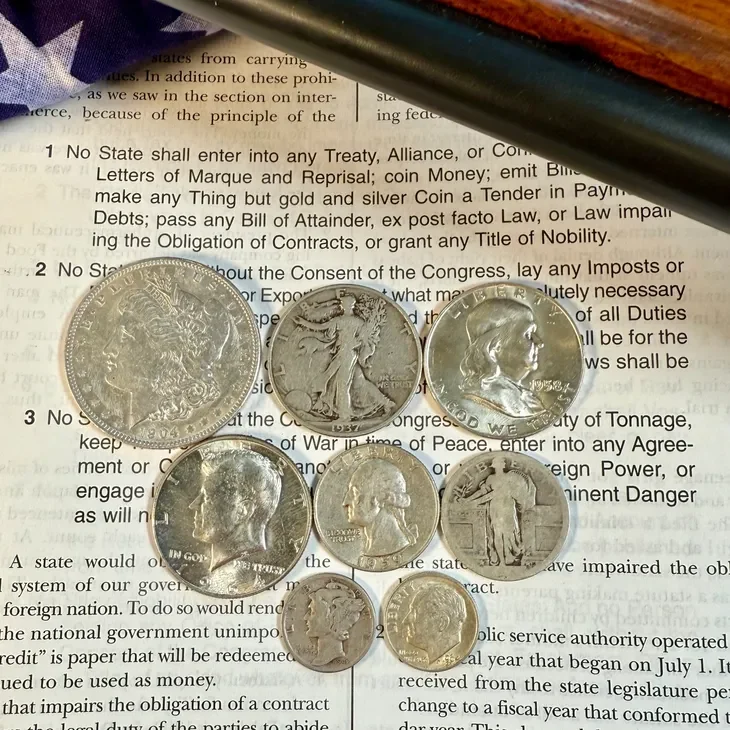 Nine silver coins on a document background.